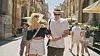 Line og Jesper med sommerhatte går ned ad en travl, solrig byshoppinggade