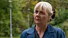 Ældre kvinde ser op med alvorligt udtryk i grøn park