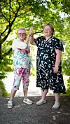 To kvinder giver highfive på en sti omgivet af grønne træer.