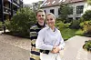 Otto og Amalie står omfavnende i en solrig gårdhave foran deres lejlighedsbygning.