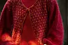 Nærbillede af rød strikket cardigan over rød bluse i sollys