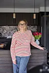 Kvinde i stribet bluse står ved køkkenø med tulipaner i baggrunden