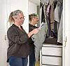 Jannie Rydahl Bjerre står ved sit åbne garderobeskab og holder et stykke tøj op.