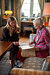 Heidi Frederikke og Dronning Margrethe sidder i stue og ser i en stor bog ved et bord.
