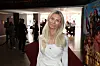 Kvinde i hvid kjole står på rød løber foran biograf med filmplakat i baggrunden