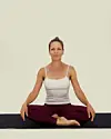 Person sidder krydsbenet på yogamåtte i oprejst meditationsstilling