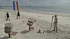 Vært og to deltagere ved konkurrenceopstilling på øde sandstrand