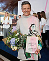 Margrethe Vestager holder blomster og diplom foran publikum ved prisuddeling.