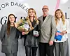 Gruppe foran ELLE-væg, midterperson holder blomster og pris