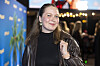 Rachel Ellebye ved premiere på 'Offroad' foran blå palmevæg og lys i baggrunden.
