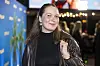 Rachel Ellebye ved premiere på 'Offroad' foran blå palmevæg og lys i baggrunden.