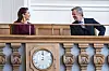 Kong Frederik X og Dronning Mary sidder smilende bag træbalustrade med ur i Folketinget.