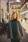 Kvinde i grøn kjole og cardigan går på solrig gade med cykler i baggrunden.