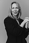 Sort-hvidt portræt af Mathilde Passer i blazer med foldede hænder mod neutral baggrund