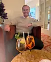 Mand i lænestol med to cocktails på bord foran sig i elegant lounge