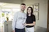 Daniel Brask og Maria Mainz står smilende sammen i en lys stue med store vinduer.
