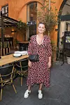 Kvinde i mønstret kjole står ved udendørsområde på Kvæler Brewpub.