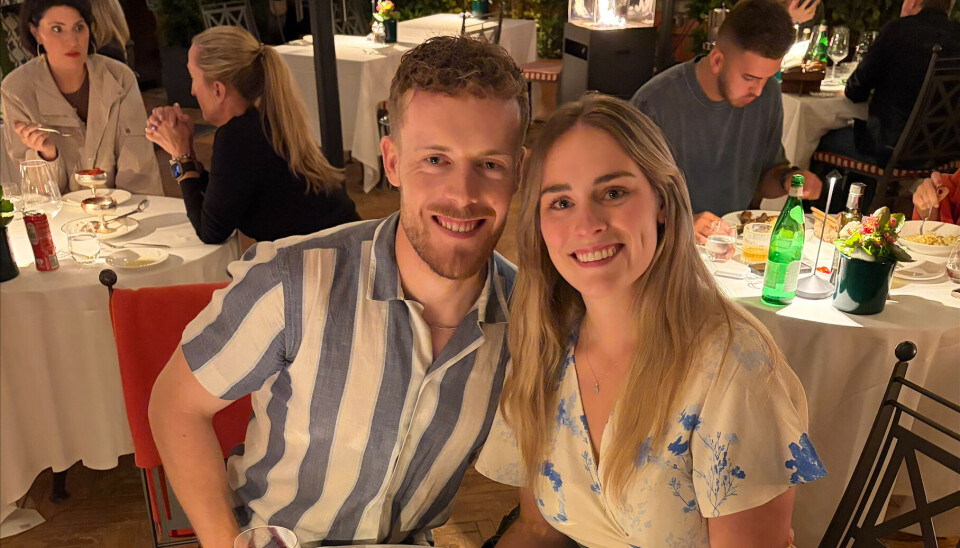 Billede 5 - Markus og Cecilie smiler ved bord på stemningsfuld restaurant med vinflasker og blomster