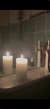 Tændt bloklys på badeværelsesvask foran spejl med tandbørster og tandpasta.