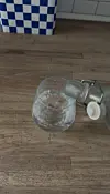 Vand hældes fra glasflaske ned i et glas på et træbord