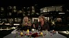To personer skåler ved et udendørs middagsbord foran et oplyst hotel om natten
