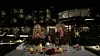 To personer skåler ved et udendørs middagsbord foran et oplyst hotel om natten