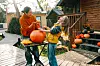 Mor og datter udhuler et stort græskar til halloween på en terrasse foran et træhus.