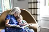 Bedstemor læser bog for barnebarn, der ligger tæt ind til hende i en lys stue