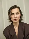 Skuespiller Katrine Greis-Rosenthal med kort vådt hår i brun oversize blazer foran lys baggrund
