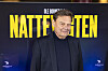 Mand foran stor gul-blå plakat for filmen Nattevagten ved premiere i biografen.