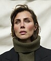 Katrine Greis-Rosenthal i olivengrøn rullekrave og mørk blazer foran lys baggrund