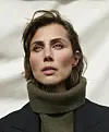 Katrine Greis-Rosenthal i olivengrøn rullekrave og mørk blazer foran lys baggrund