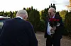 Janus Nielsen holder en rød blomsterbuket ved en bil på en udendørs parkeringsplads.