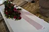 Hvid kiste med blomster og lyserødt bånd i kirkerum for Merethe Kasten