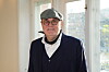 Janus Nielsen med kasket og jakkesæt ved et solbelyst vindue på kontor.