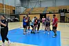 Kvindehåndboldhold samles på banen i en indendørs sportshal