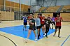 Gruppe håndboldspillere laver øvelse på indendørs bane i sportshal