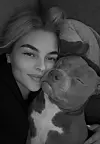 Kvinde ligger i sofaen med ansigtet tæt mod en sovende hund i sort-hvidt foto